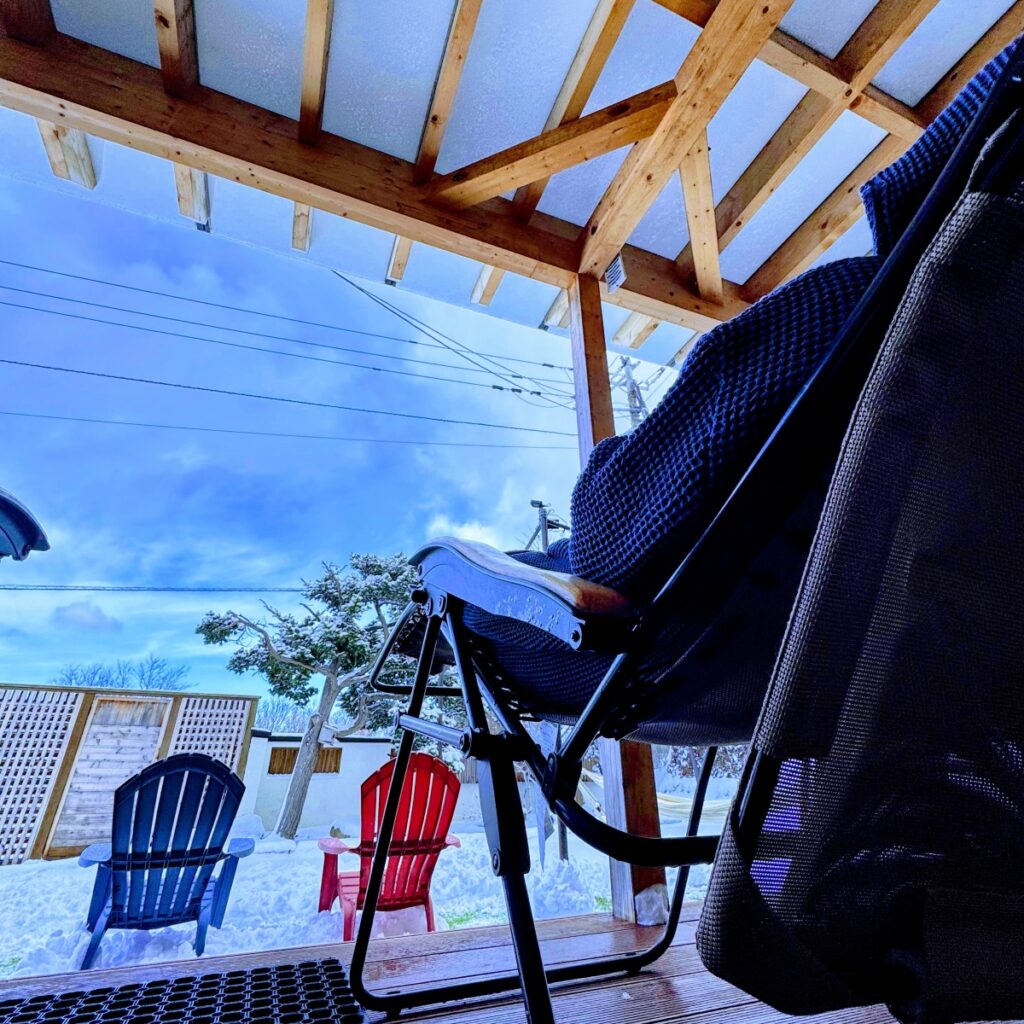 雪景色の庭を望むウッドデッキの写真が挿入されている。写真には、屋根付きテラスに置かれた黒いインフィニティチェア、雪の積もった庭に置かれた青と赤のアディロンダックチェアが写っている。画像には編集用のツールバーが表示されている。