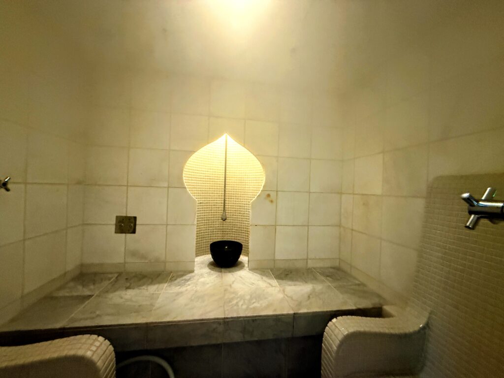 サーマルクライムスタジオ富士のスチームサウナ「テルマリウム」の内部。モロッコ風の白いタイル張りと、イスラム様式のアーチ型をしたライトアップされたアルコーブ、大理石調のベンチが特徴的な、幻想的で美しい空間。