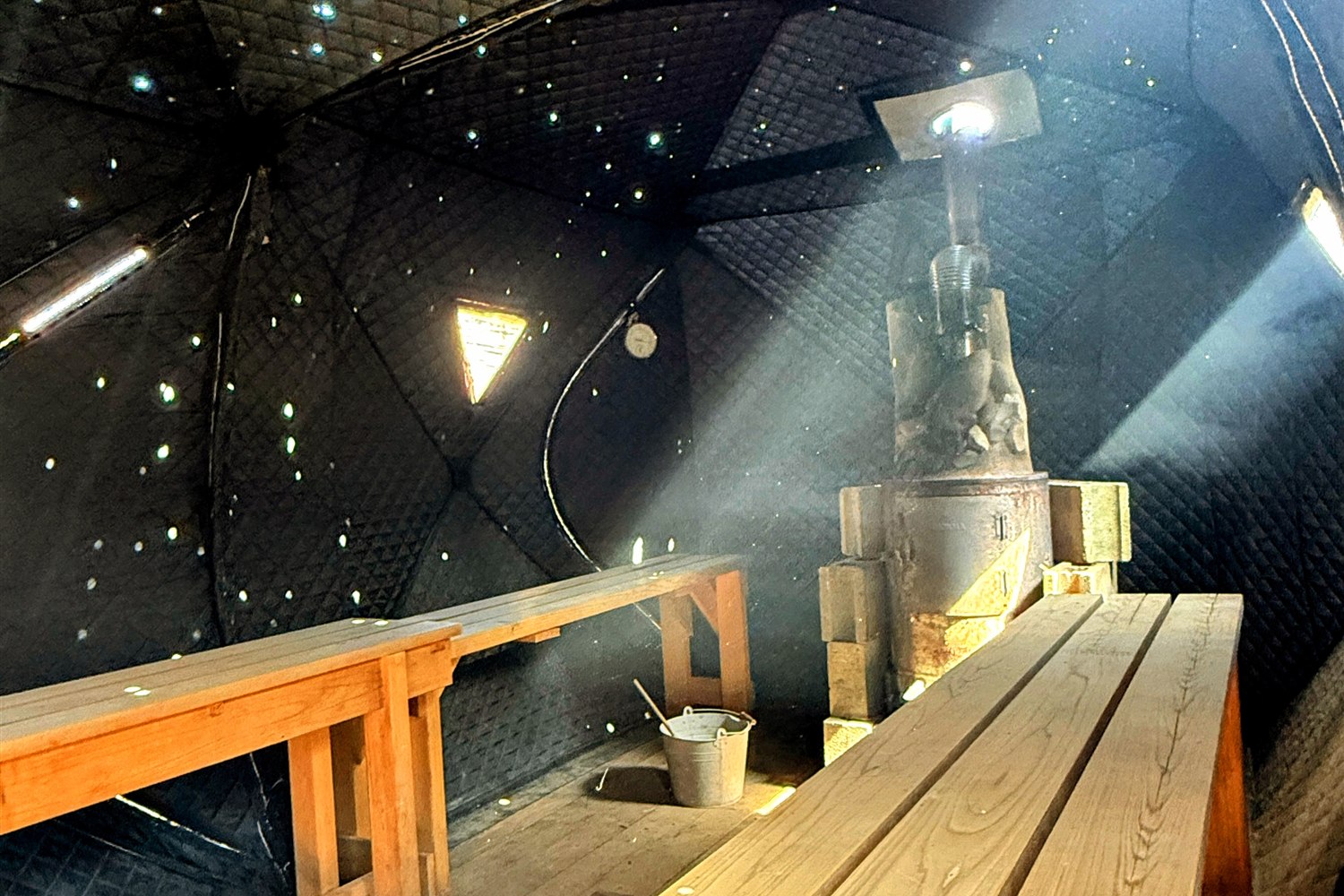 ℃HILL VALLEY 養老渓谷のドーム型テントサウナ内部。天井の無数のライトが星空のように輝き、薪ストーブとサウナストーンが据えられている