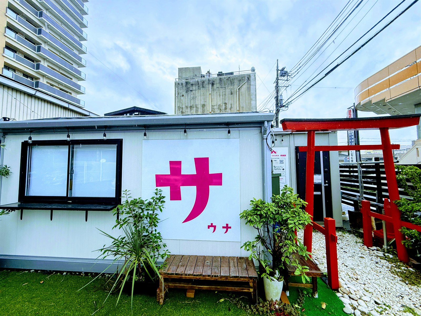 FUJIYAMA SAUNA倶楽部の外観。白い建物に大きな「サ」ロゴと赤い鳥居