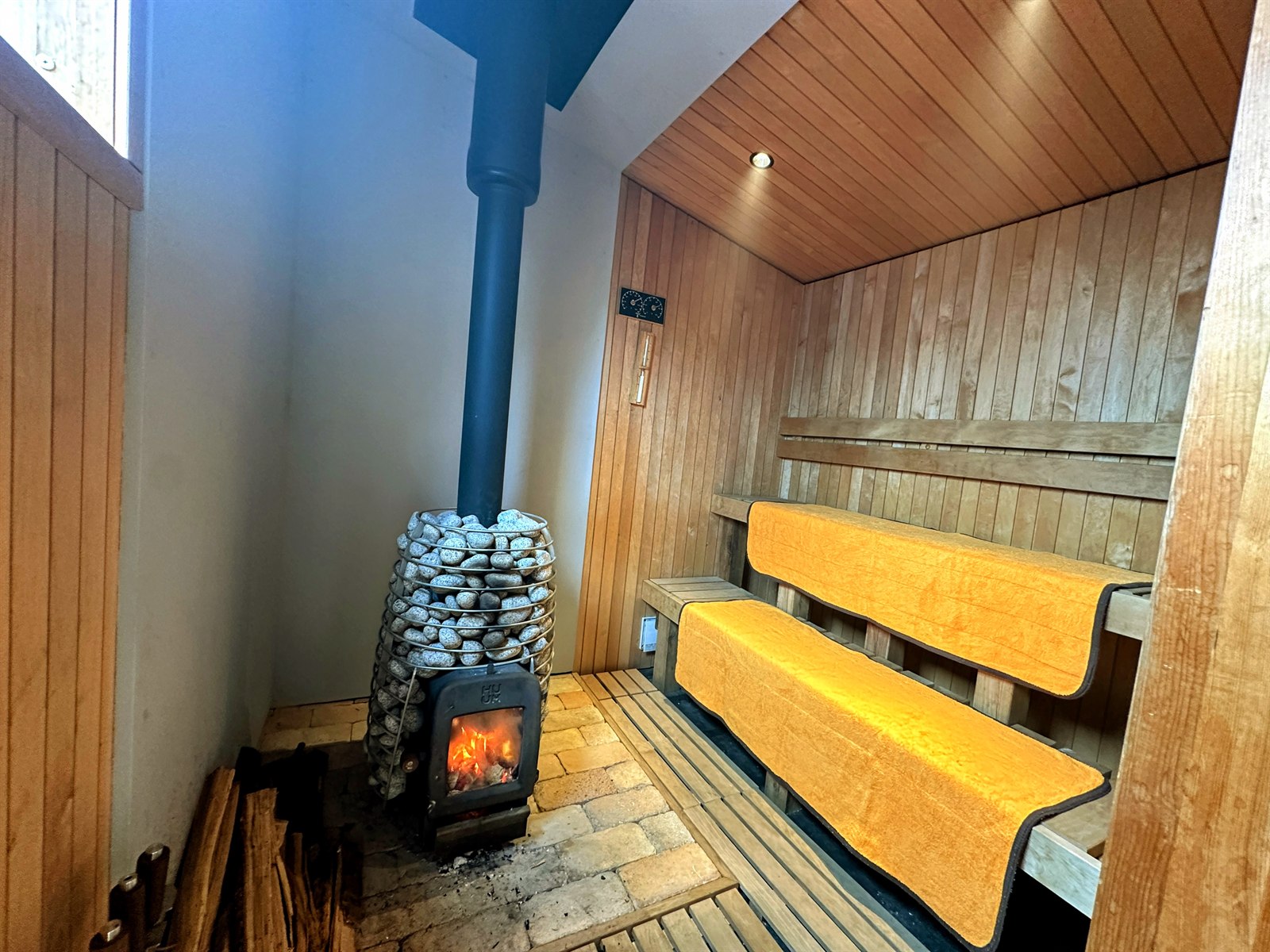 ogawa GRAND lodge FIELDのサウナ室内部。HUUMの薪ストーブにサウナストーンが山盛り、2段のベンチ
