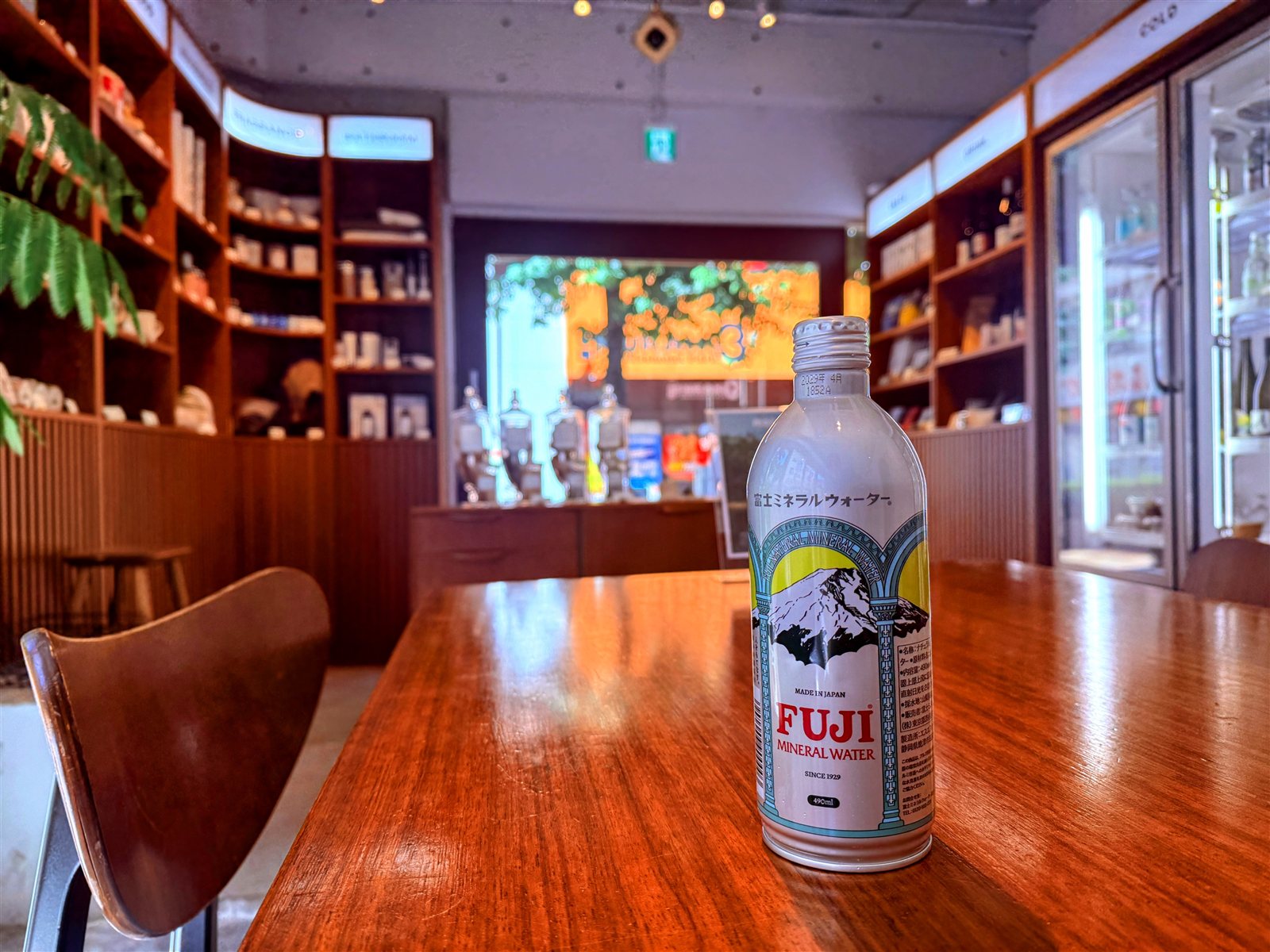 PRIVATE SAUNA maa & GROCERYのグロッサリー店内。木の棚に食料品やボトルが並び、テーブルにFUJIミネラルウォーターが置かれている