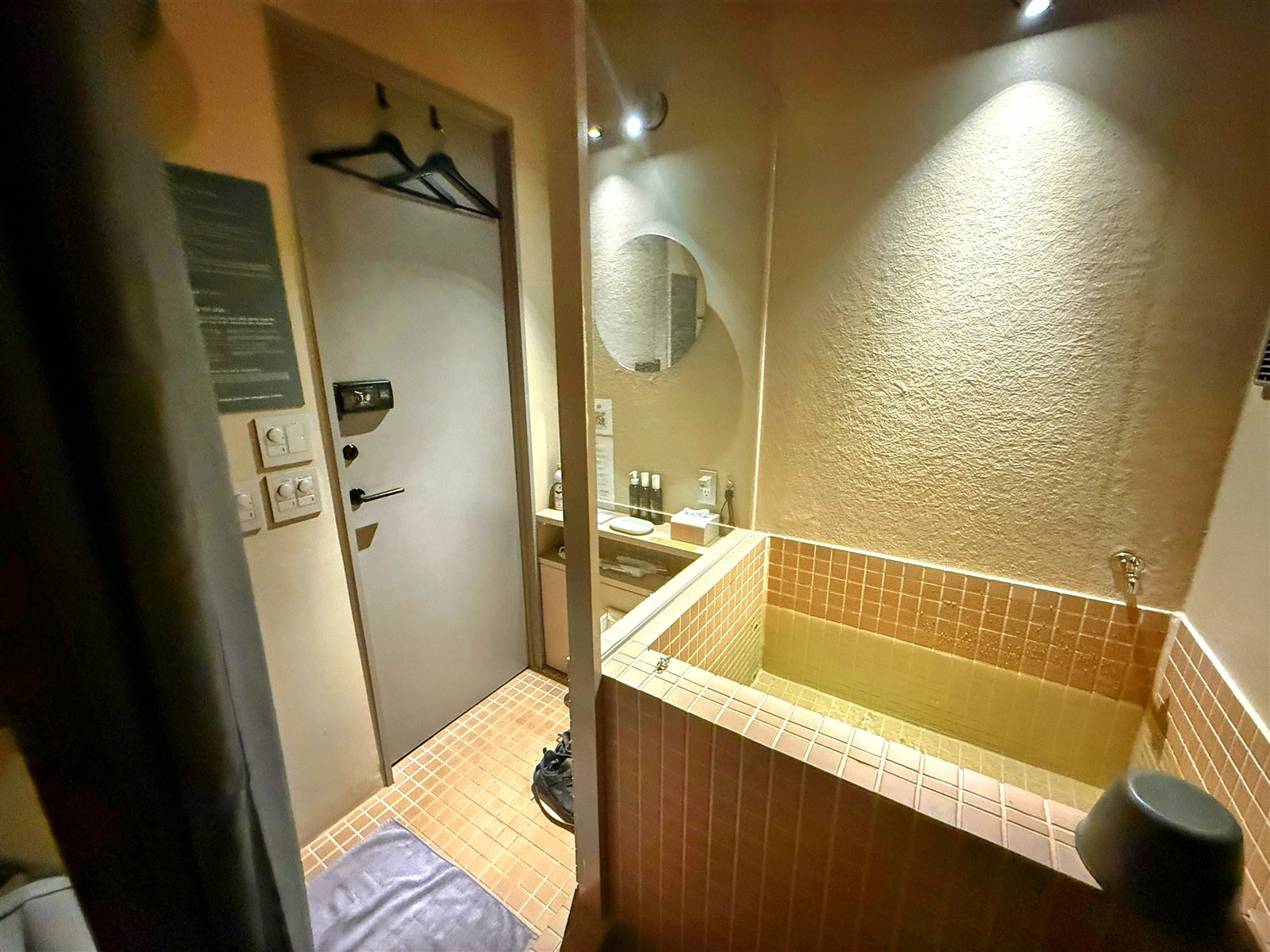 PRIVATE SAUNA maa & GROCERYの個室。入口ドアと着替えスペース、タイル張りの水風呂、丸鏡とアメニティ