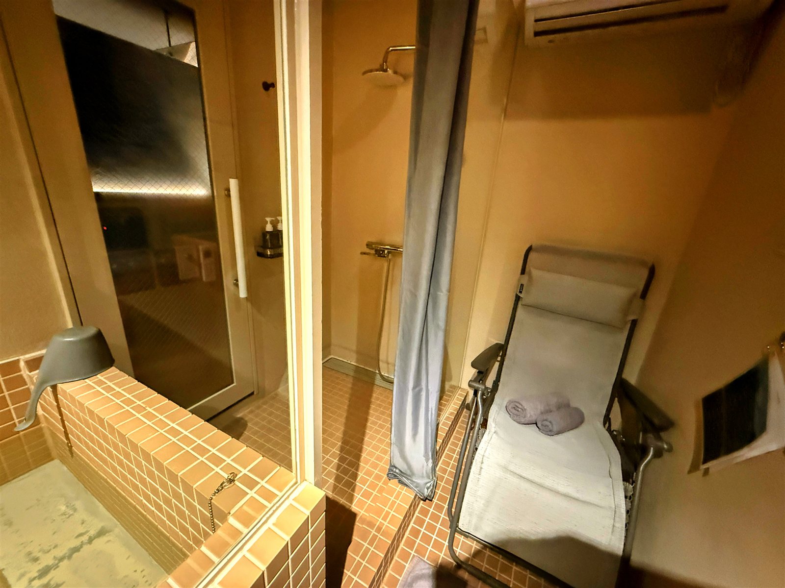 PRIVATE SAUNA maa & GROCERYの個室内。タイル張りの水風呂とシャワー、インフィニティチェア、頭上のエアコン