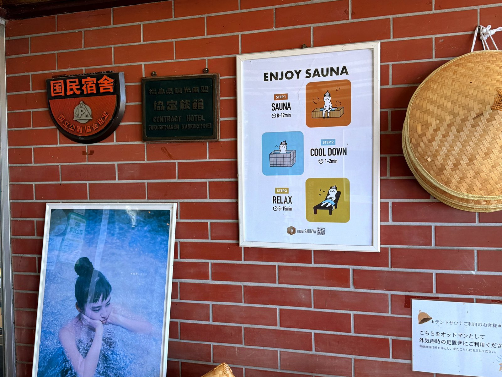 MINATOYA SAUNAの受付まわり。ENJOY SAUNAの入り方ポスターや国民宿舎の銘板、貸出用の菅笠が並ぶ