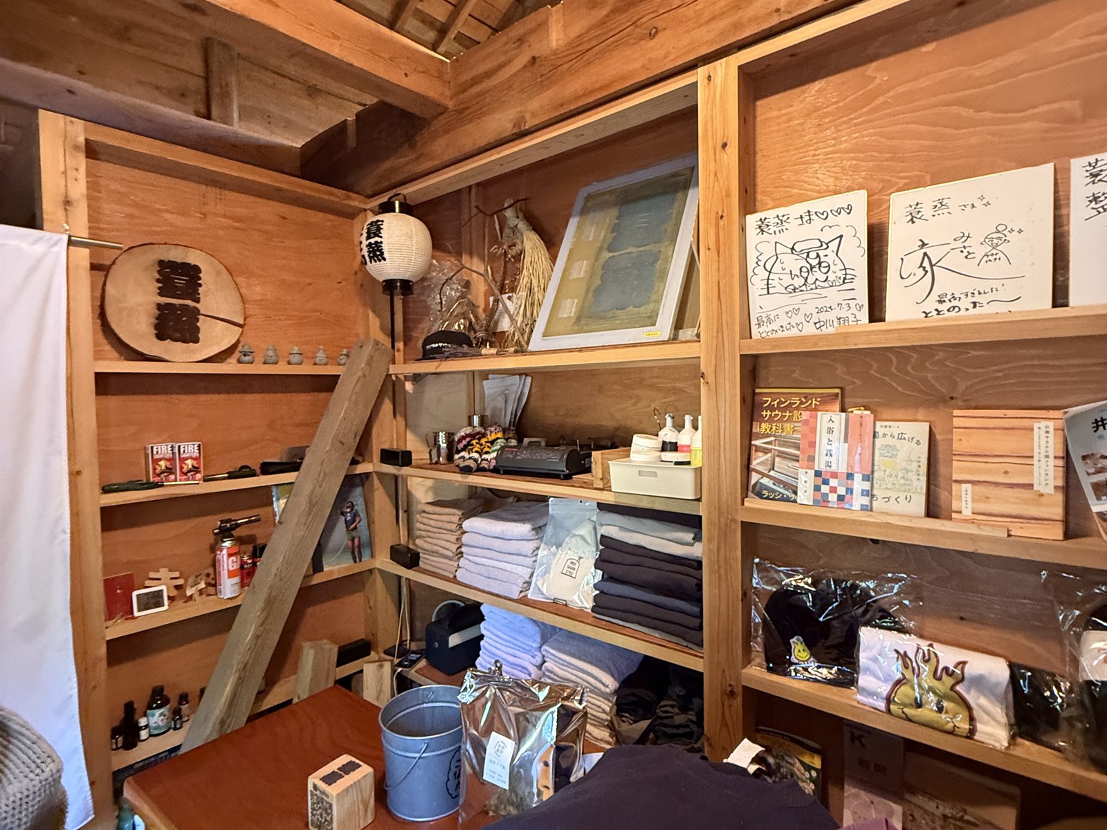 サウナ蓑蒸の受付・物販スペース。木造の温かみのある空間にタオルやグッズが並ぶ