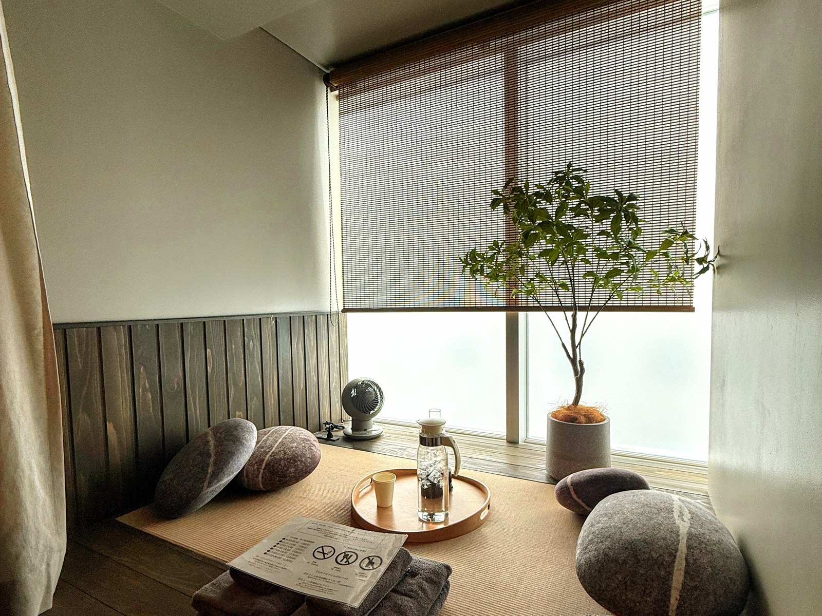 SAUNA OOO SAPPOROの休憩スペース。畳の上に石をかたどったクッションと窓辺の観葉植物