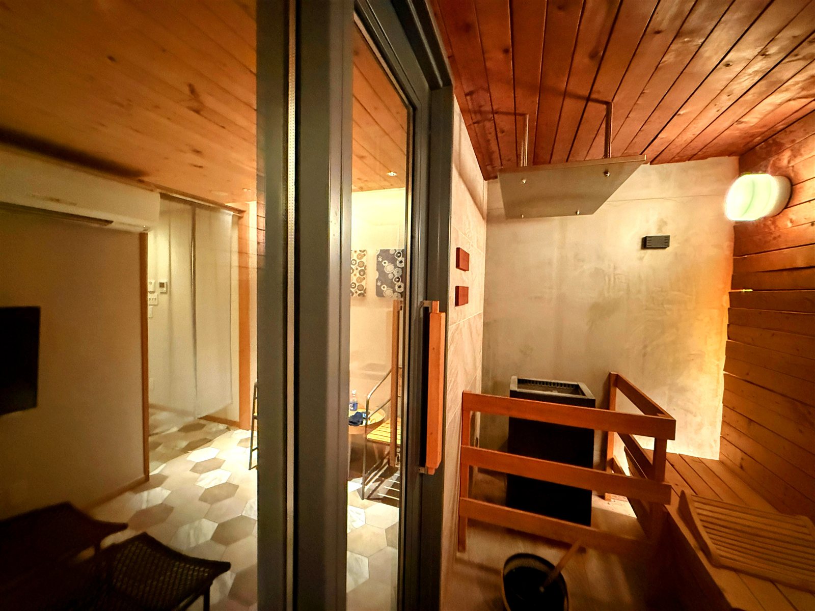 yksi SAUNA & STAYのサウナ室からガラス越しに休憩スペースを見た様子。サウナ・水風呂・休憩がひとつの個室で完結する動線