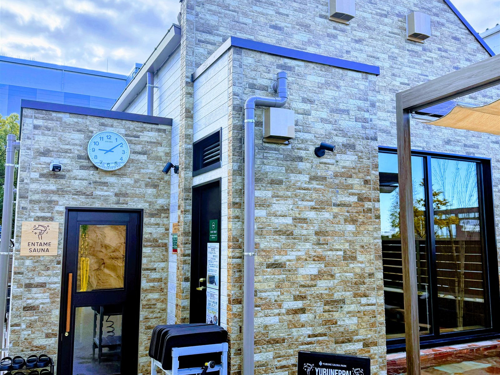 YUBUNE SAUNA PARKのエンタメサウナの外観。ストーン調の建物に「ENTAME SAUNA」の看板、本日のアウフグース（YUBUNEPPA!）スケジュール黒板