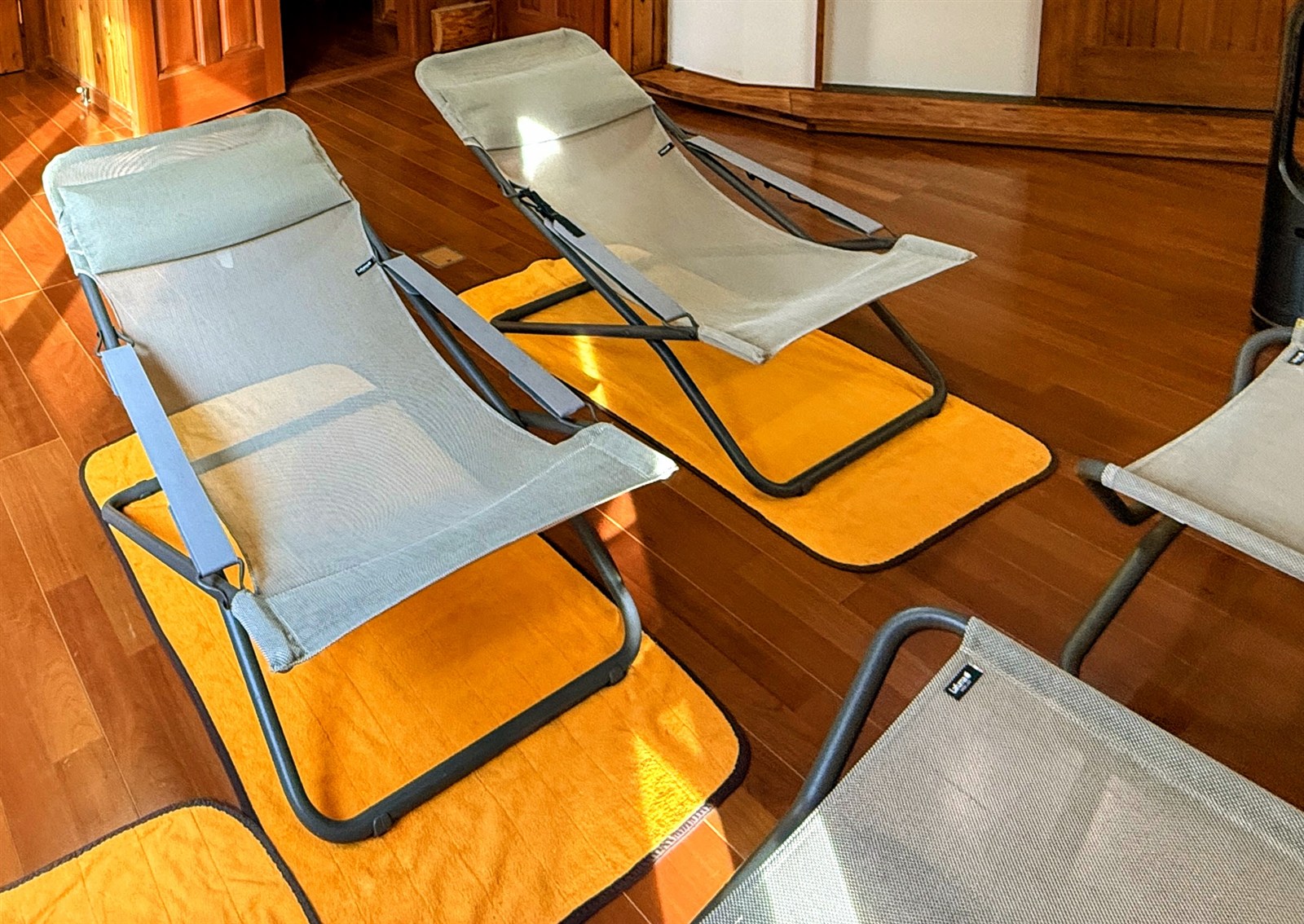 赤城ログイン（AKAGI LOG INN）のログハウス内の内気浴スペースに置かれたLafuma TRANSABED DUO。淡いグレーのメッシュ生地とX字フレームのデッキチェア2脚