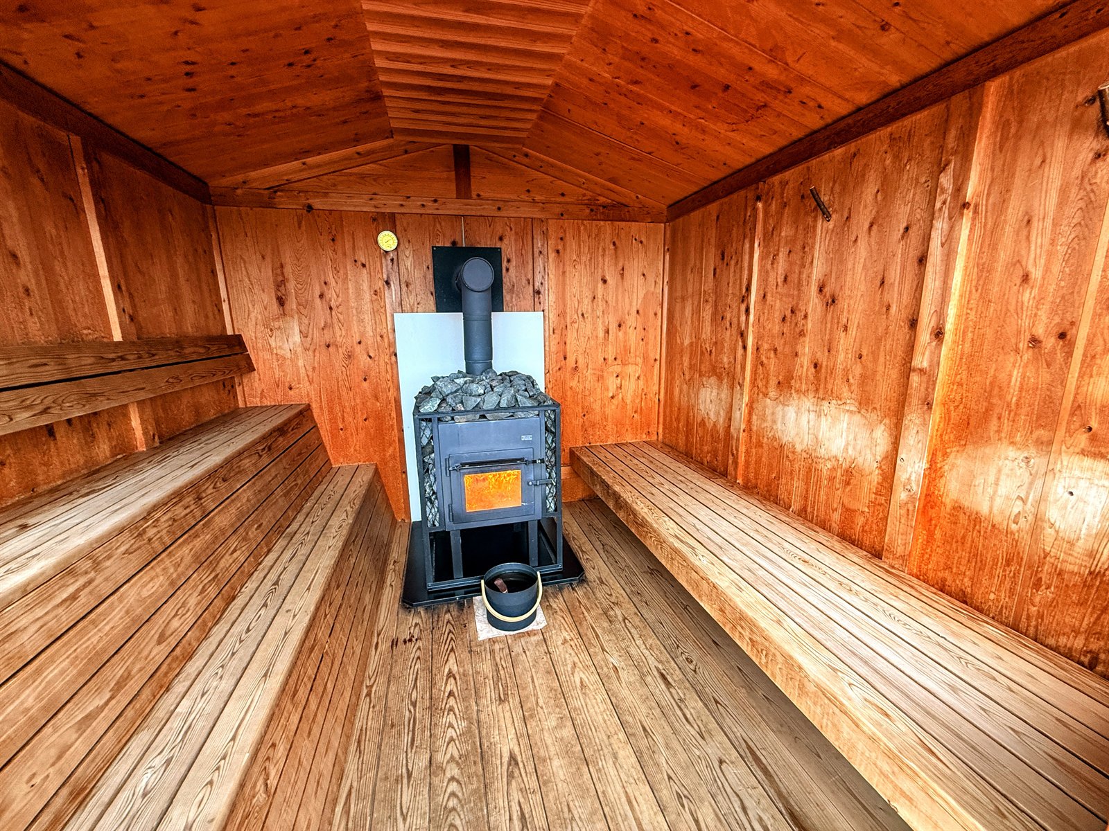 薪ストーブとサウナストーンのある小屋サウナ内観
