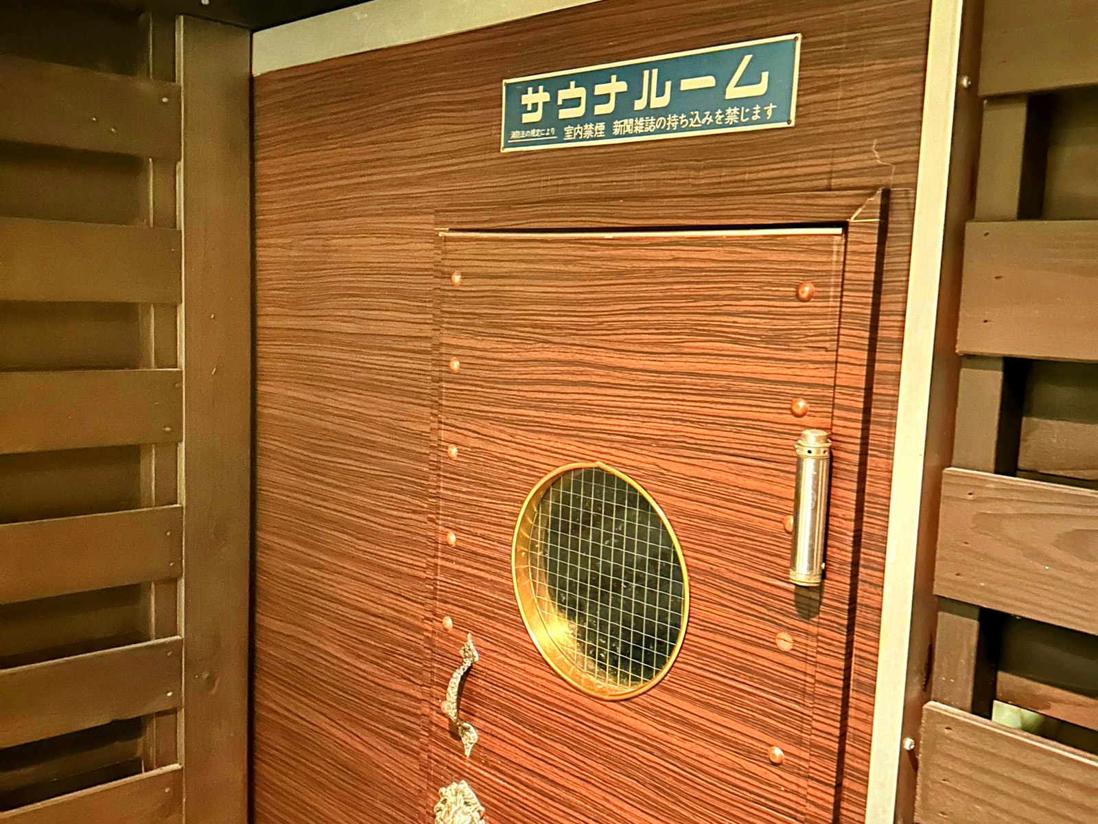 HOTEL SEEDS 桶川店の客室内サウナのドア。サウナルームの看板と手巻き式のSAUNA CONTROLタイマー