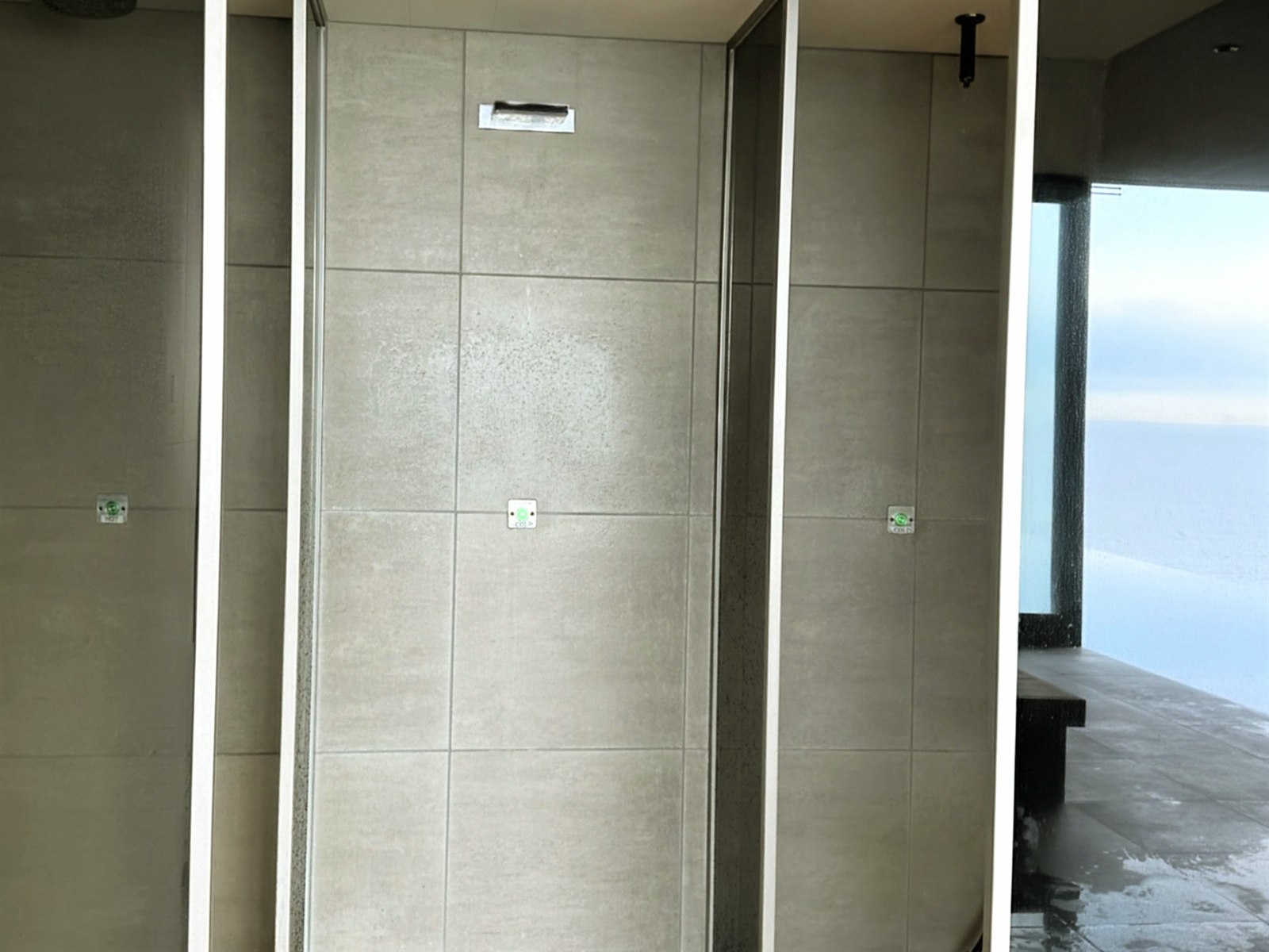 THERMAL SPA S.WAVEのシャワーブース。海の見える窓の横に並ぶ3連のシャワー